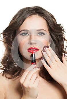 Perfect brunette woman holding red lipstick in hand with dark red manicured nails. Beauty and cosmetics concept, closeup beauty