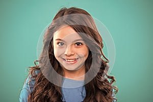 Perfect curling hair. Kid girl long healthy shiny hair. Kid happy cute face with adorable curly hairstyle stand over