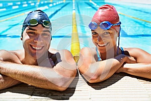 The perfect day for a swim. Two young swimmers smiling broadly at the camera as they stand in the pool.