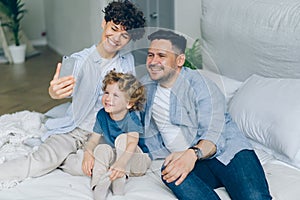 Perfect family girl guy and kid taking selfie at home in bed using smartphone