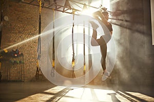 Perfect flexibility. Full length of athletic woman in black sport clothing jumping while exercising in professional semi