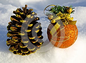 Perfect gold christmas ball with ribbon and cone on snow