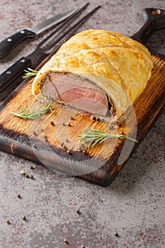 Perfect homemade juicy Beef Wellington, tenderloin dish on rustic wooden board. Vertical