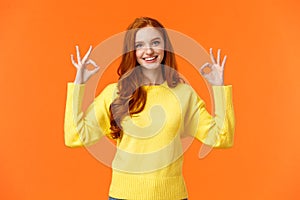 Perfect idea concept, acception. Good-looking redhead girl in yellow sweater, showing okay, good or approval sign