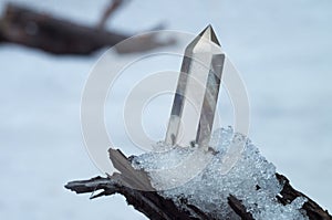 Perfect large shining crystal of transparent quartz in the sunlight on natural snow winter background close-up
