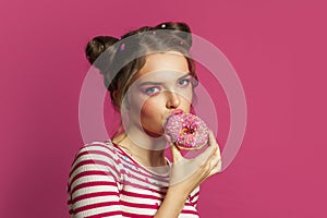 Perfect model woman eating testy donut on colorful pink background