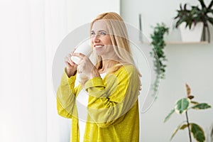 Perfect morning. Woman drinking coffee near window photo