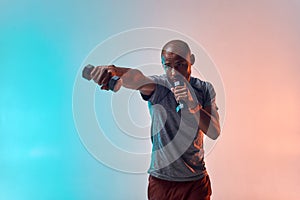 Perfect muscles. Strong young african man exercising with dumbbells while standing against colorful background