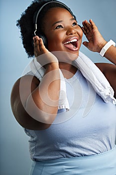 The perfect music to get the blood pumping. Studio shot of an athletic young woman looking excited while posing against