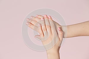 Perfect pink manicure on nails. Beautiful woman hand with clean skin over pink backdrop.