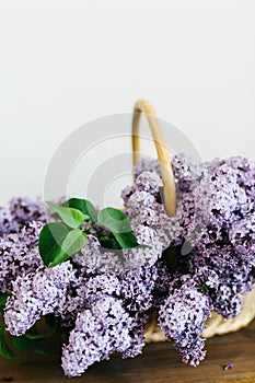 Perfect purple lilac flowers bunch in a basket on wooden table