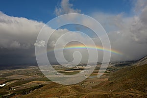 A perfect rainbow against a blue sky and clouds