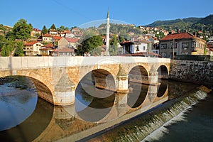 Perfect reflections of Sehercehaja Bridge in the Miljacka river, with Alifakovac district in the background