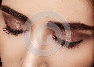 Perfect shape of eyebrows, brown eyeshadows and long eyelashes. Closeup macro shot of fashion smoky eyes visage