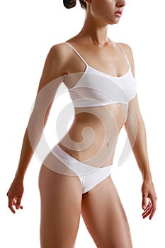 Perfect, slim, toned, young body of a girl in white underwear posing isolated on white. Plastic surgery and aesthetic