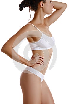 Perfect, slim, toned, young body of a girl in white underwear posing isolated on white. Plastic surgery and aesthetic