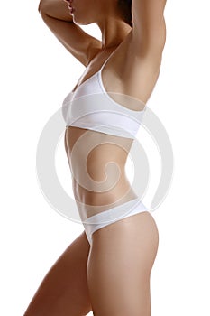 Perfect, slim, toned, young body of a girl in white underwear posing isolated on white. Plastic surgery and aesthetic