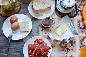 Perfect soft boiled eggs, piece of bread, butter,tomatoes,cup of coffee. Sloppy homemade breakfast