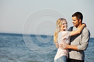 The perfect spot for a bit of loving. Portrait of a happy young couple hugging each other at the ocean.
