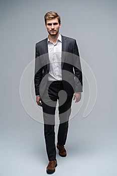 Perfect suit. Full length of handsome young man in suit looking at camera while standing against gray background