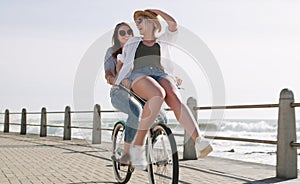 The perfect summer date. Full length shot of a happy young couple riding a bicycle together on a promenade near the