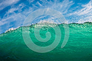 Perfect surfing wave in sea. Breaking turquoise wave with sun light