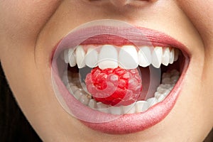 Perfect teeth biting raspberry.