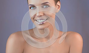 Perfect teeth smile with shiny lips. Beautiful close-up of a tanned face of a young woman with clean fresh skin.