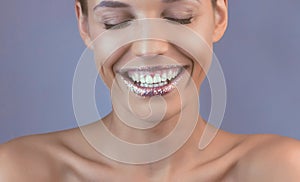 Perfect teeth smile with shiny lips. Beautiful close-up of a tanned face of a young woman with clean fresh skin.