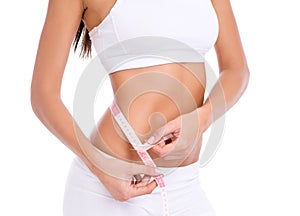 A perfect waistline. Cropped studio shot of a fit young woman taking her measurements isolated on white.