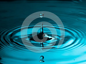 Perfect water drop splashing into smooth water causing ripples