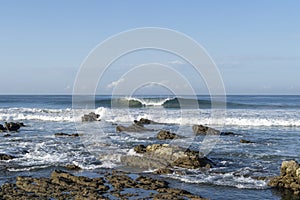 Perfect wave breaking behind the rocks