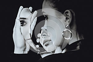 Perfect woman looking at broken mirror on black background, black and white portrait