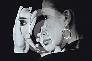 Perfect woman looking at broken mirror on black background, black and white portrait photo