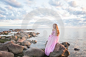 Perfect woman in pink dress dreaming outdoors near sea