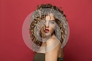 Perfect young woman model with curly hairstyle on red background