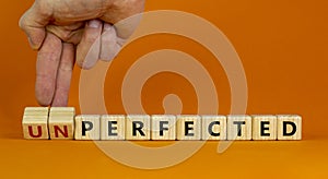 Perfected or unperfected symbol. Businessman turns wooden cubes and changes the word unperfected to perfected on a beautiful