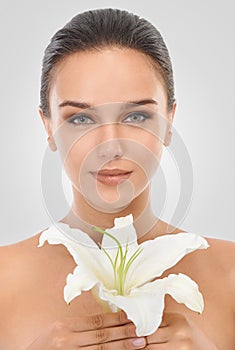 Perfecting perfection. Studio beauty shot of an attractive brunette woman holding a flower.