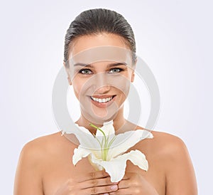 Perfecting perfection. Studio beauty shot of an attractive brunette woman holding a flower.