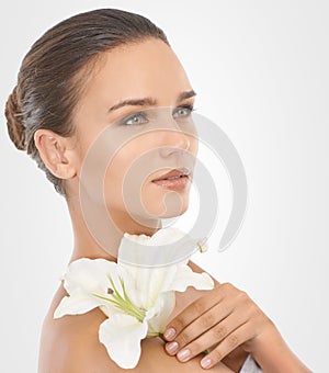 Perfecting perfection. Studio beauty shot of an attractive brunette woman holding a flower.