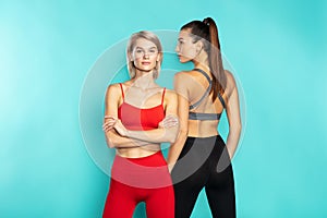 Perfection. Two beautiful sporty girls in sportswear posing in studio against blue background. Keeping their body fit