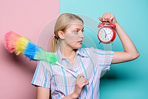 Perfectionism concept. Woman hold dust brush alarm clock. Everything must be perfect. Girl perfectionist. Perfectionist