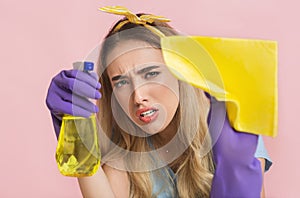 Perfectionism at home cleaning concept. Concentrated housewife wipes stain on camera with spray and sponge