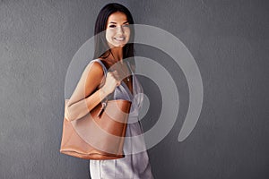 Perfectly accessorized with my bag. Studio portrait of an attractive young woman holding her handbag.