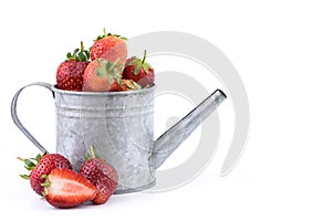 Perfectly retouched fresh strawberry fruit with sliced half in silver colored watering can on white background.