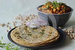 Perfectly round Paratha. Indian flatbread made of wheat flour topped with sesame seeds and coriander leaves served with white