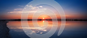 Perfectly specular reflection on the Molentargius pond in Cagliari at sunset. Panoramic view.