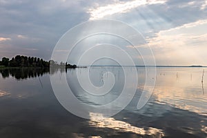 Perfectly symmetric and spectacular view of a lake, with clouds, sky and sun rays reflecting on water