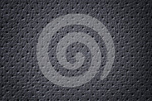 Perforated dark gray leather texture background, closeup. Black backdrop from wrinkle skin