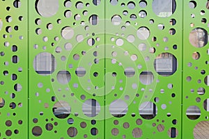 Perforated metal textured facade in bright light green color. Background for industrial design